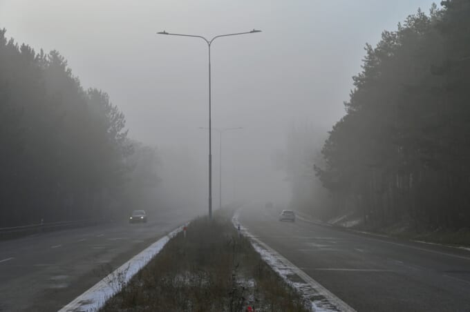 Cars in the fog. Bad winter weather and dangerous automobile traffic on the road. Light vehicles in foggy day.