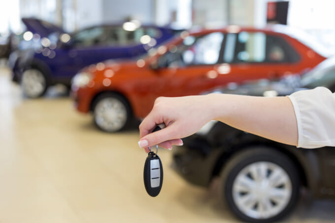Saleswoman holding keys to a new car.