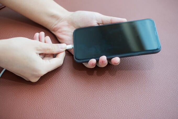 Woman hands charging battery in mobile smart phone in the sofa a