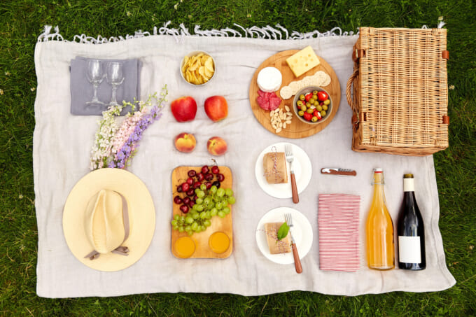 food, drinks and picnic basket on blanket on grass
