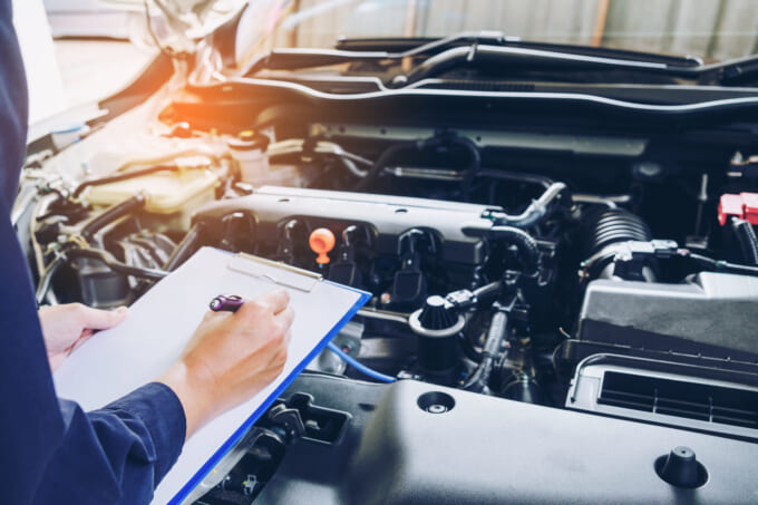 mechanic holding a clipboard of service order working in garage.